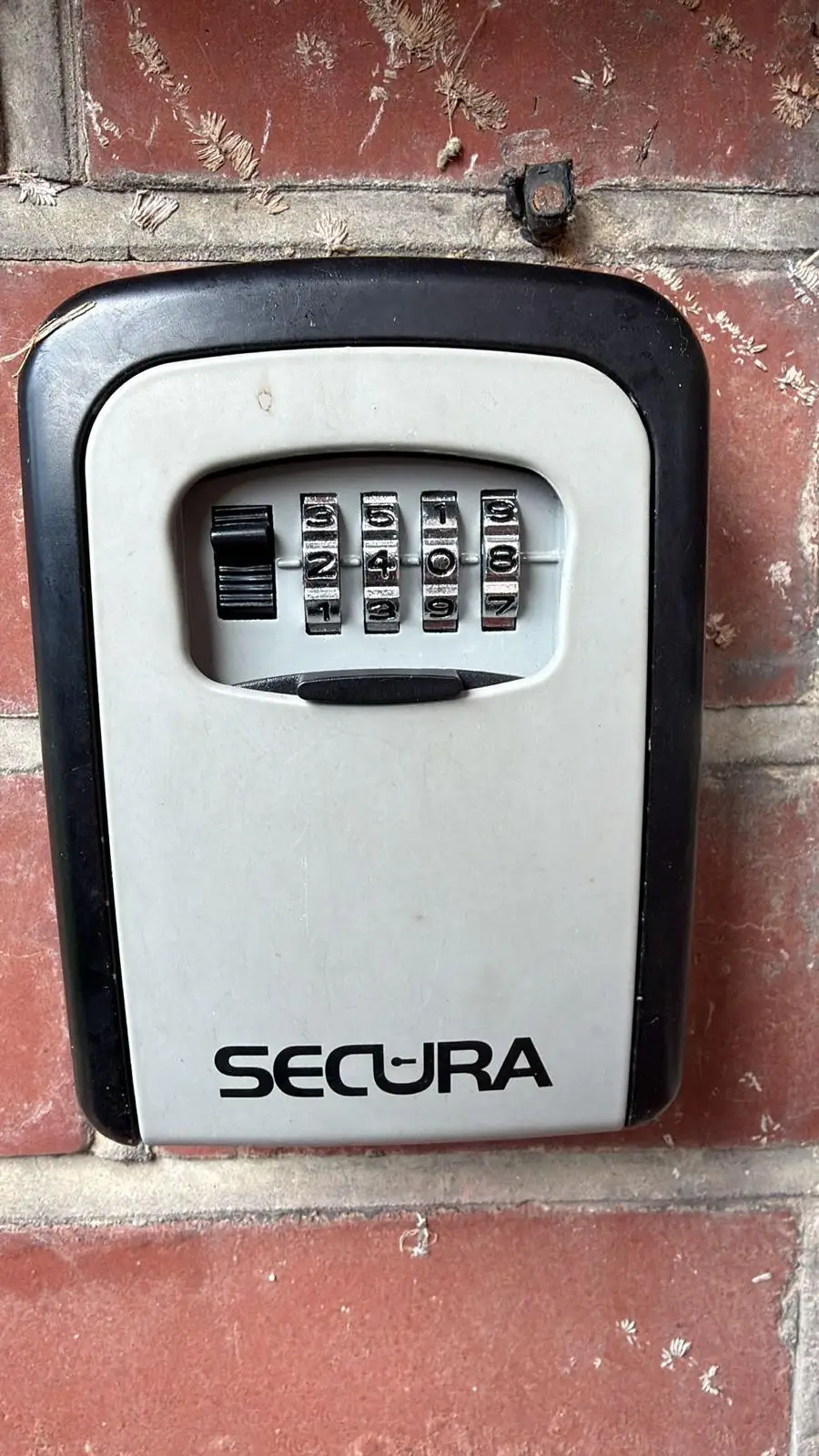 A combination key safe fixed to a brick wall